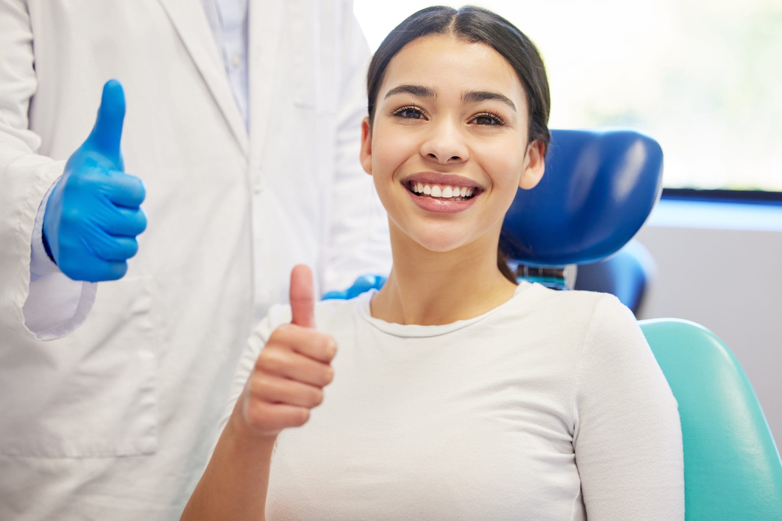 ten-out-of-ten-teeth-portrait-of-a-young-woman-showing-thumbs-up-while-visiting-the-dentist